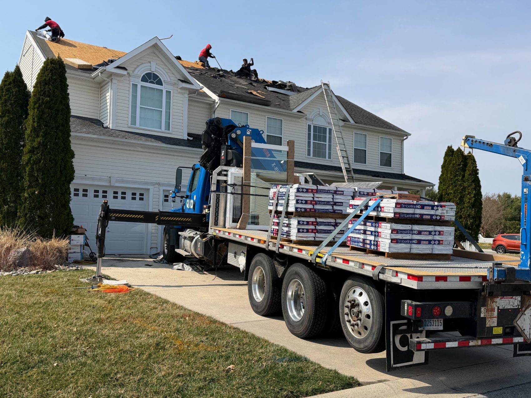 HomePros crew tearing off an old roof with a crane truck delivering GAF Timberline shingles